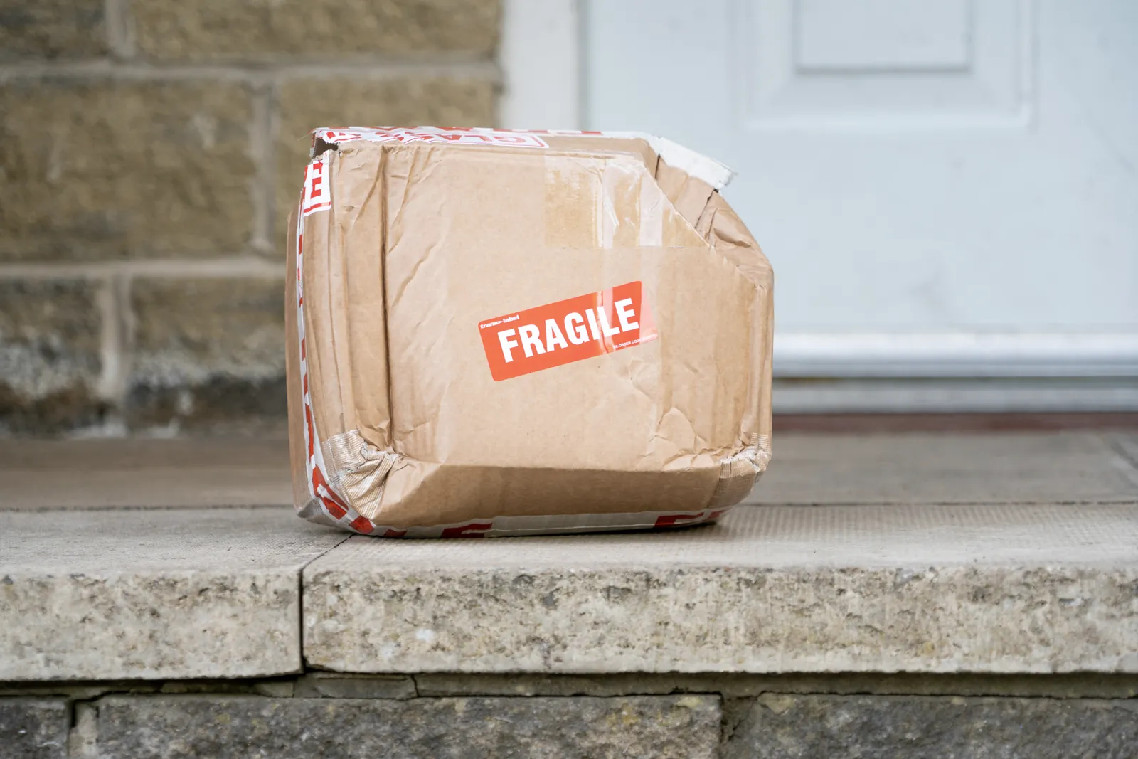 Una caja de cartón marcada como frágil, ya entregada en la puerta de casa